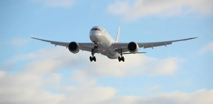 Commercial aircraft preparing to land against a blue sky