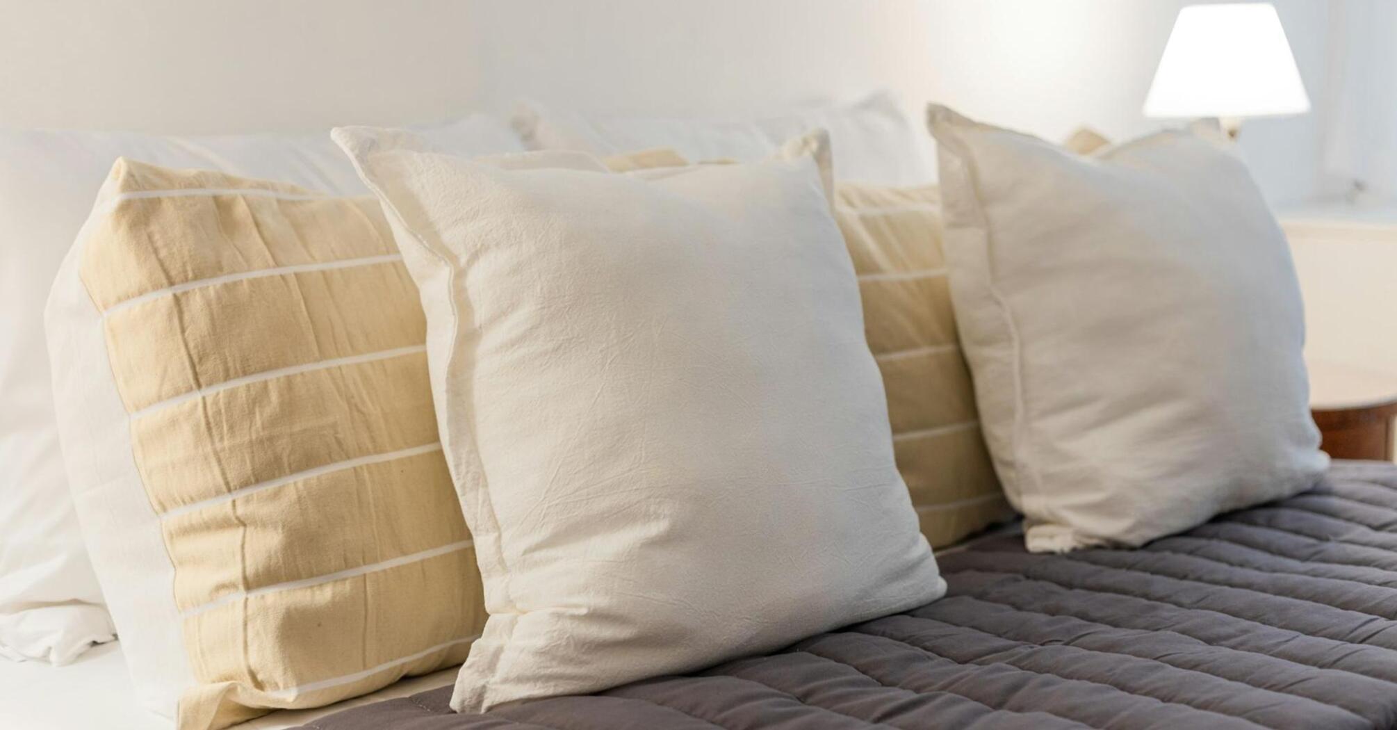 Close-up of soft beige and white pillows on a neatly made hotel bed