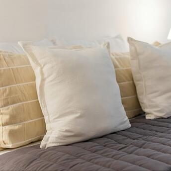 Close-up of soft beige and white pillows on a neatly made hotel bed