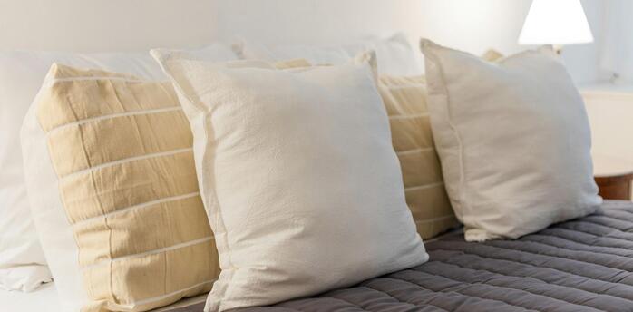 Close-up of soft beige and white pillows on a neatly made hotel bed