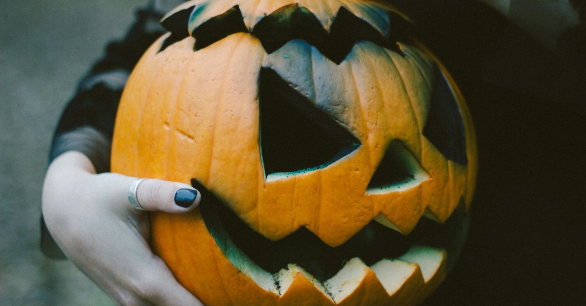 Hands holding a carved Halloween pumpkin with a glowing smile