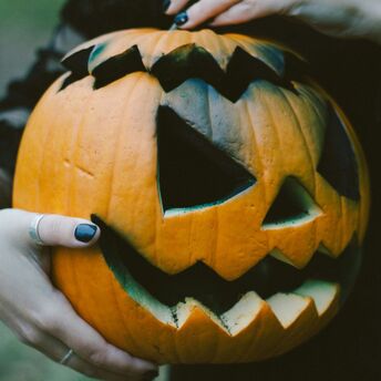 Hands holding a carved Halloween pumpkin with a glowing smile