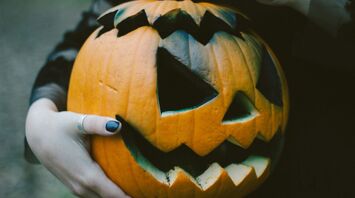 Hands holding a carved Halloween pumpkin with a glowing smile