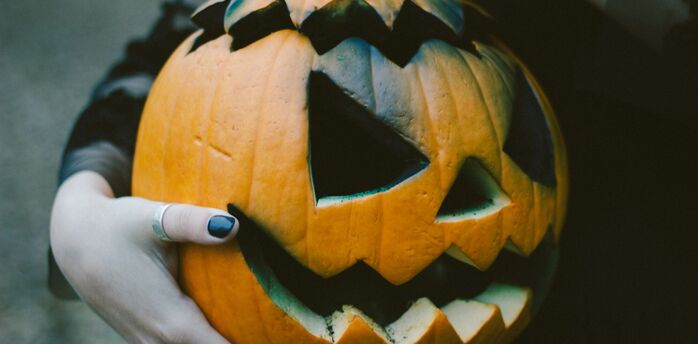 Hands holding a carved Halloween pumpkin with a glowing smile