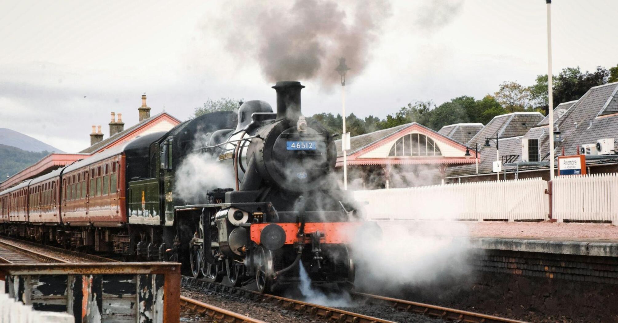 Steam locomotive at a countryside station preparing for departure