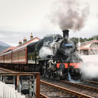 Steam locomotive at a countryside station preparing for departure