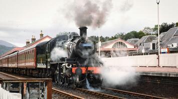 Steam locomotive at a countryside station preparing for departure