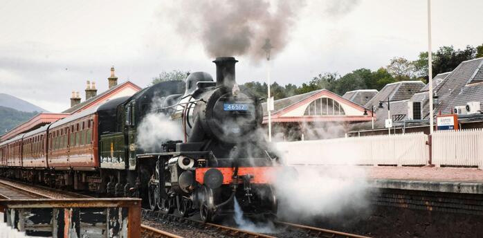 Steam locomotive at a countryside station preparing for departure