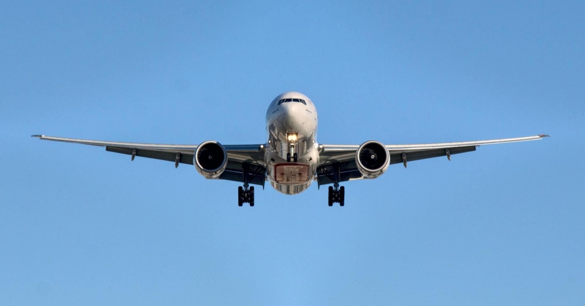 Airplane approaching runway against clear blue sky