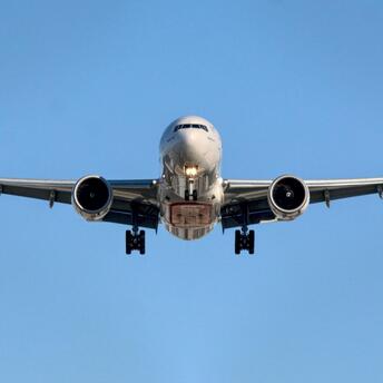 Airplane approaching runway against clear blue sky