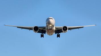Airplane approaching runway against clear blue sky