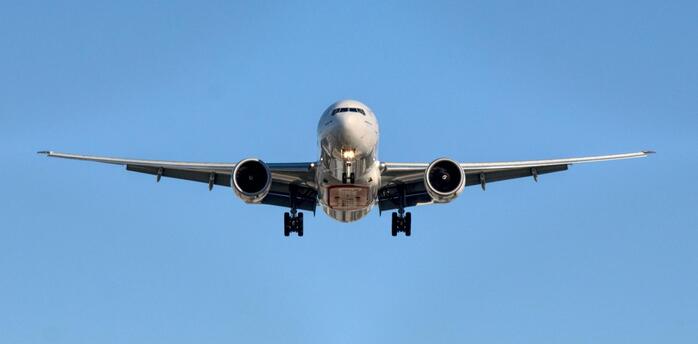 Airplane approaching runway against clear blue sky
