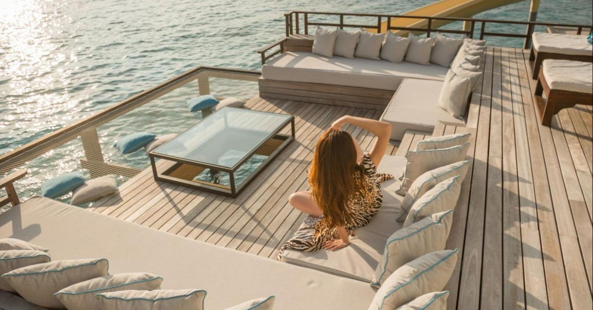 Woman relaxing on a sun deck overlooking the sea at sunset