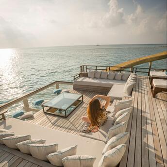 Woman relaxing on a sun deck overlooking the sea at sunset