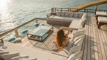 Woman relaxing on a sun deck overlooking the sea at sunset