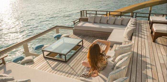 Woman relaxing on a sun deck overlooking the sea at sunset