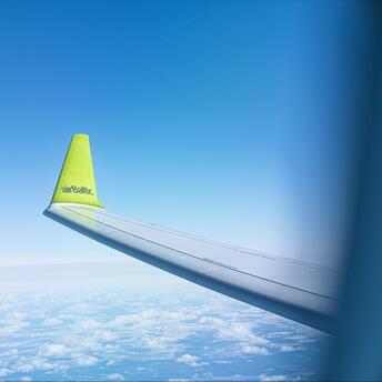 airBaltic aircraft wing flying above the clouds on a clear day