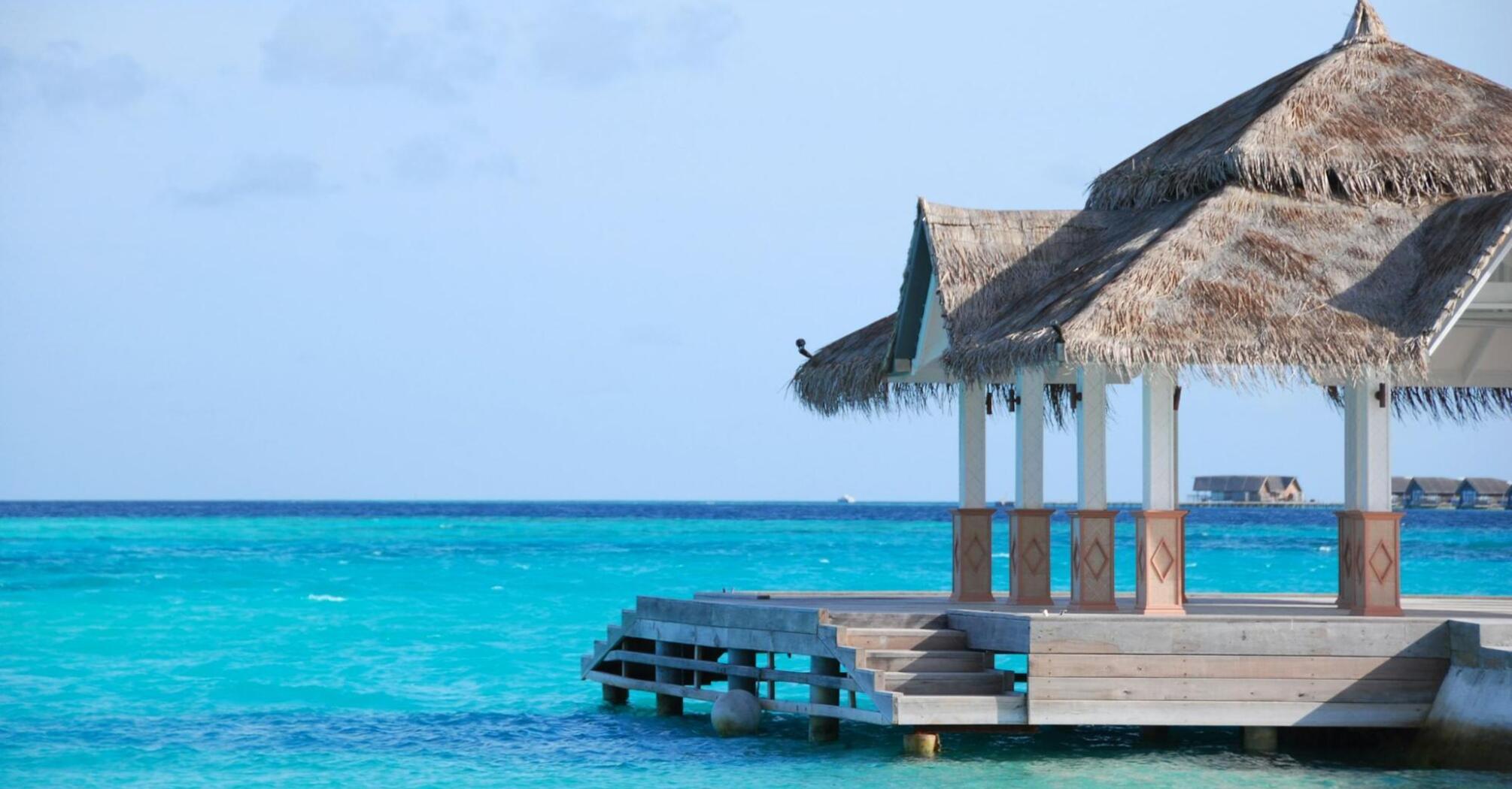 A thatched-roof pavilion overlooking clear turquoise water in the Maldives
