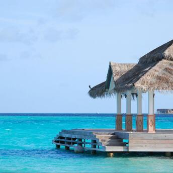 A thatched-roof pavilion overlooking clear turquoise water in the Maldives