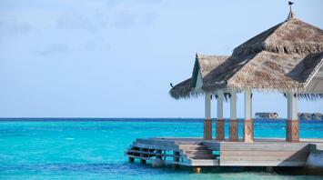 A thatched-roof pavilion overlooking clear turquoise water in the Maldives