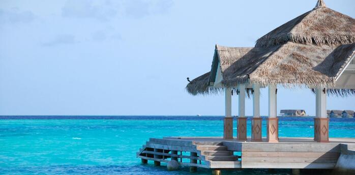 A thatched-roof pavilion overlooking clear turquoise water in the Maldives