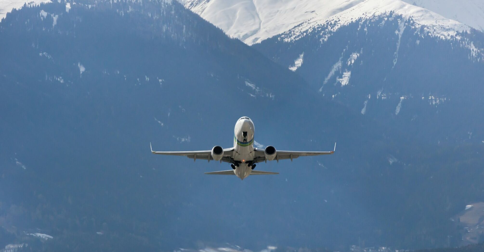 Airplane taking off over snow-covered Alps in winter