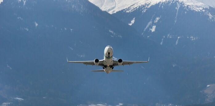 Airplane taking off over snow-covered Alps in winter