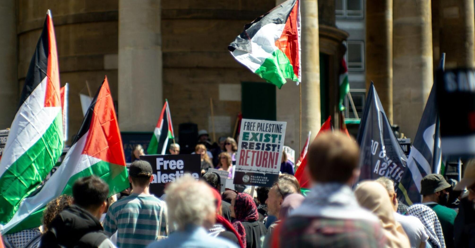 Crowd holding Palestinian flags and protest signs during a public demonstration in Italy
