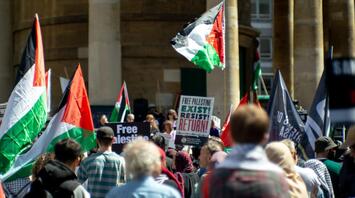 Crowd holding Palestinian flags and protest signs during a public demonstration in Italy