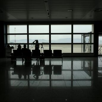 Passengers waiting in a quiet airport terminal during flight disruptions