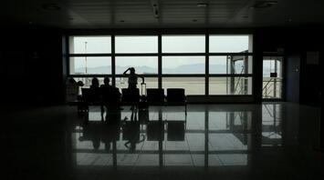 Passengers waiting in a quiet airport terminal during flight disruptions