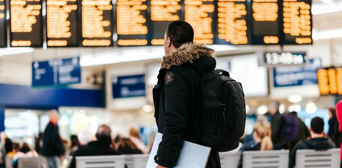 Traveler checking flight departures screen at airport terminal