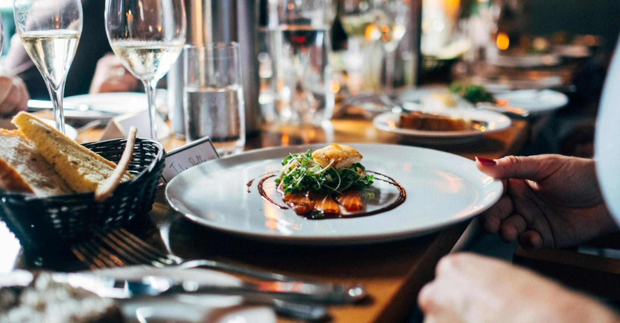 Fine dining table setting with plated dish and wine glasses