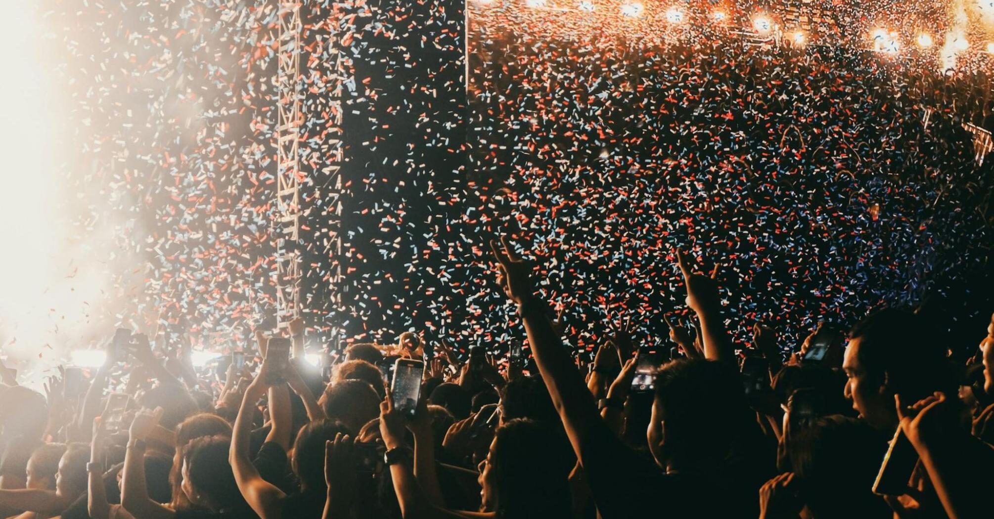 Crowd celebrating under confetti at a live music festival