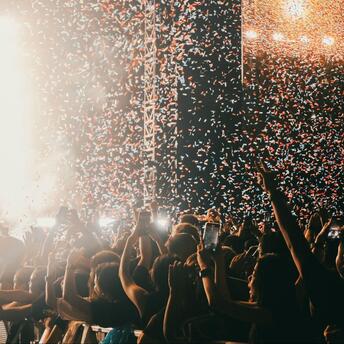 Crowd celebrating under confetti at a live music festival