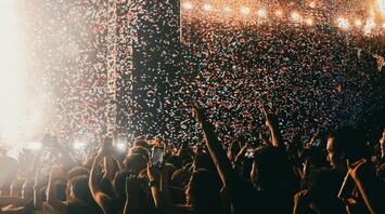 Crowd celebrating under confetti at a live music festival