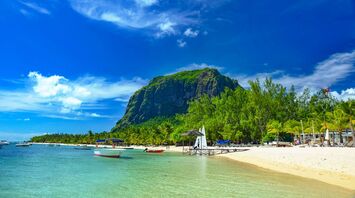 Tropical beach in Mauritius with clear water, boats, and Le Morne Brabant mountain