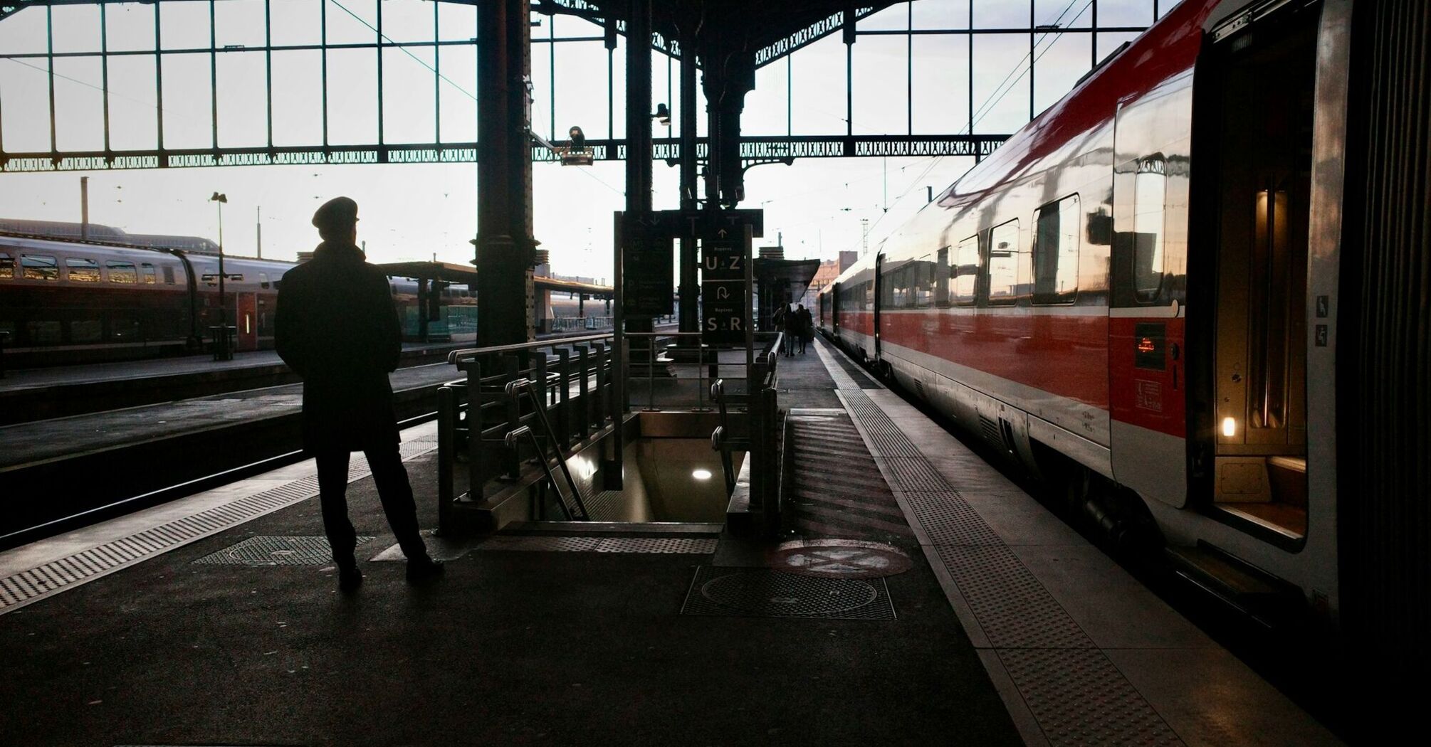 Silhouette of a traveler waiting beside a night train at a European railway station