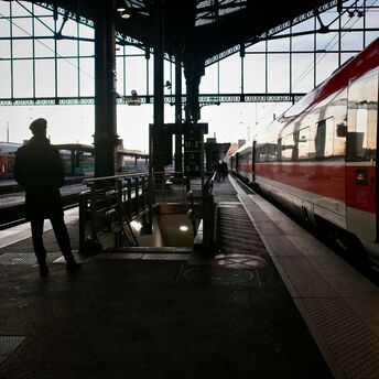 Silhouette of a traveler waiting beside a night train at a European railway station