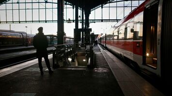 Silhouette of a traveler waiting beside a night train at a European railway station