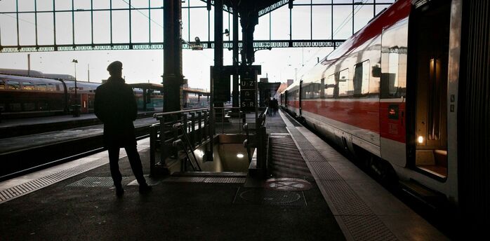 Silhouette of a traveler waiting beside a night train at a European railway station