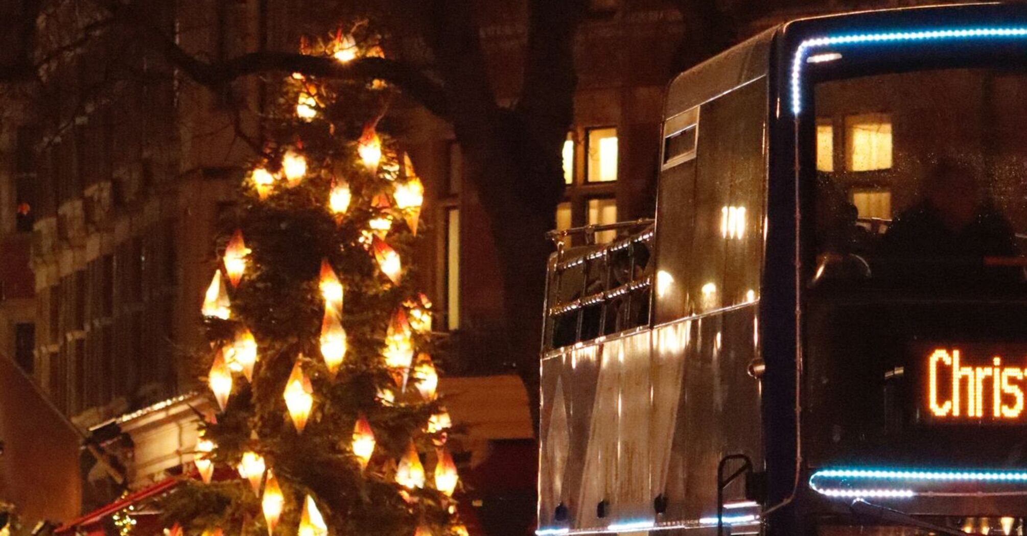 Christmas bus passing decorated streets with festive lights