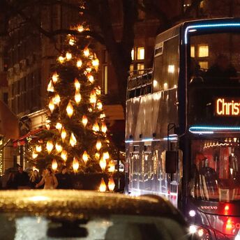 Christmas bus passing decorated streets with festive lights