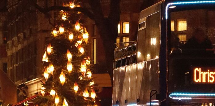 Christmas bus passing decorated streets with festive lights