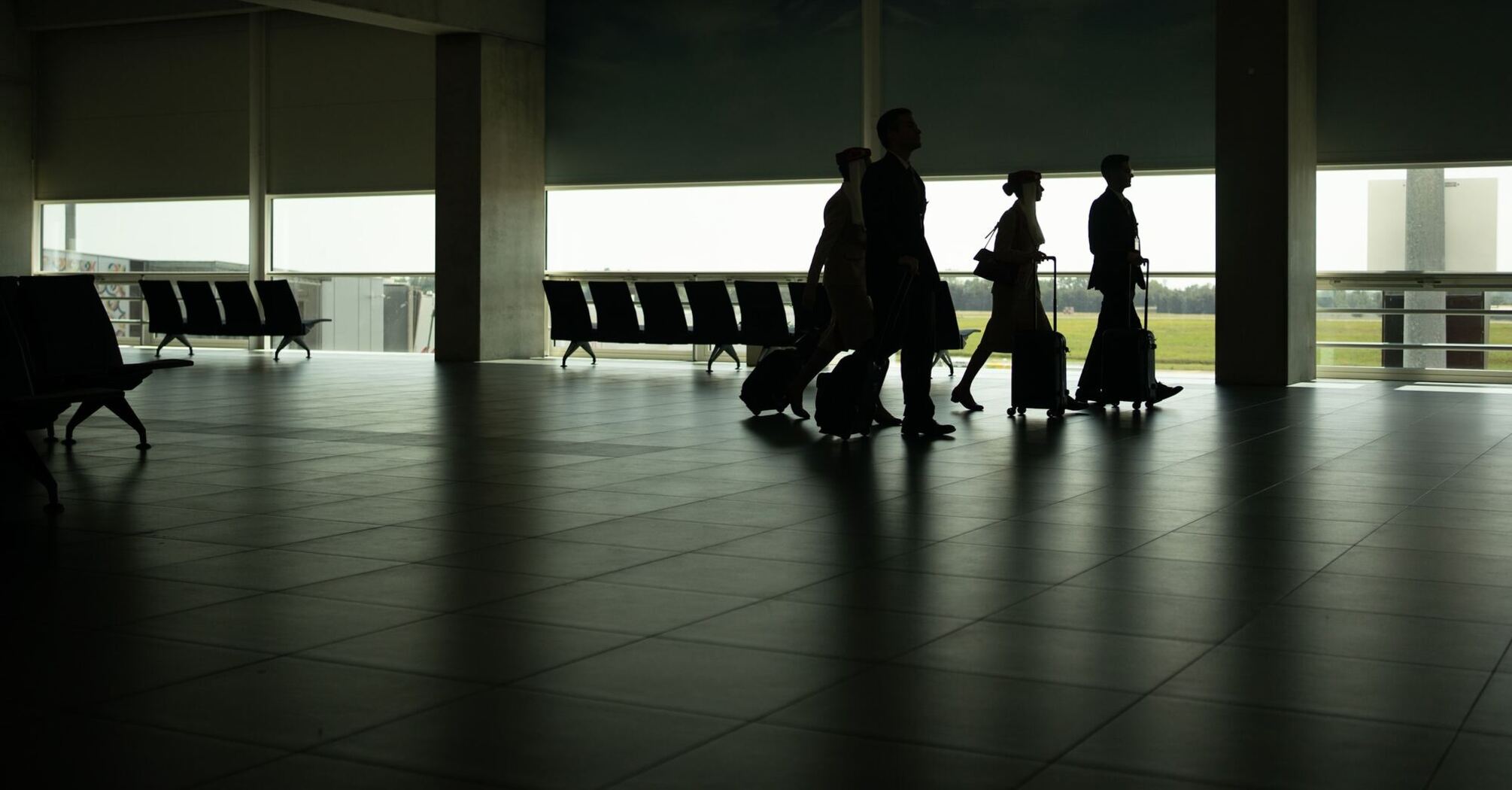 Passengers walking through a quiet airport terminal with luggage