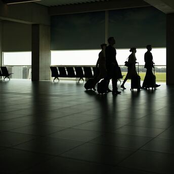 Passengers walking through a quiet airport terminal with luggage