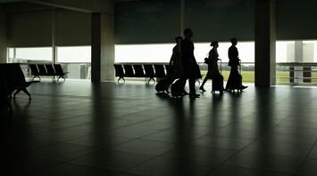 Passengers walking through a quiet airport terminal with luggage