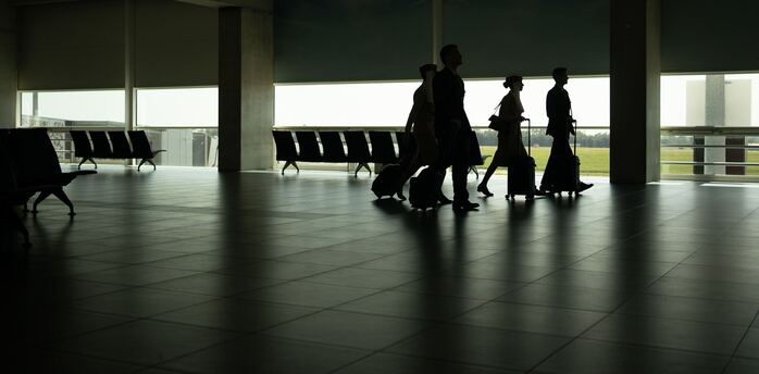 Passengers walking through a quiet airport terminal with luggage
