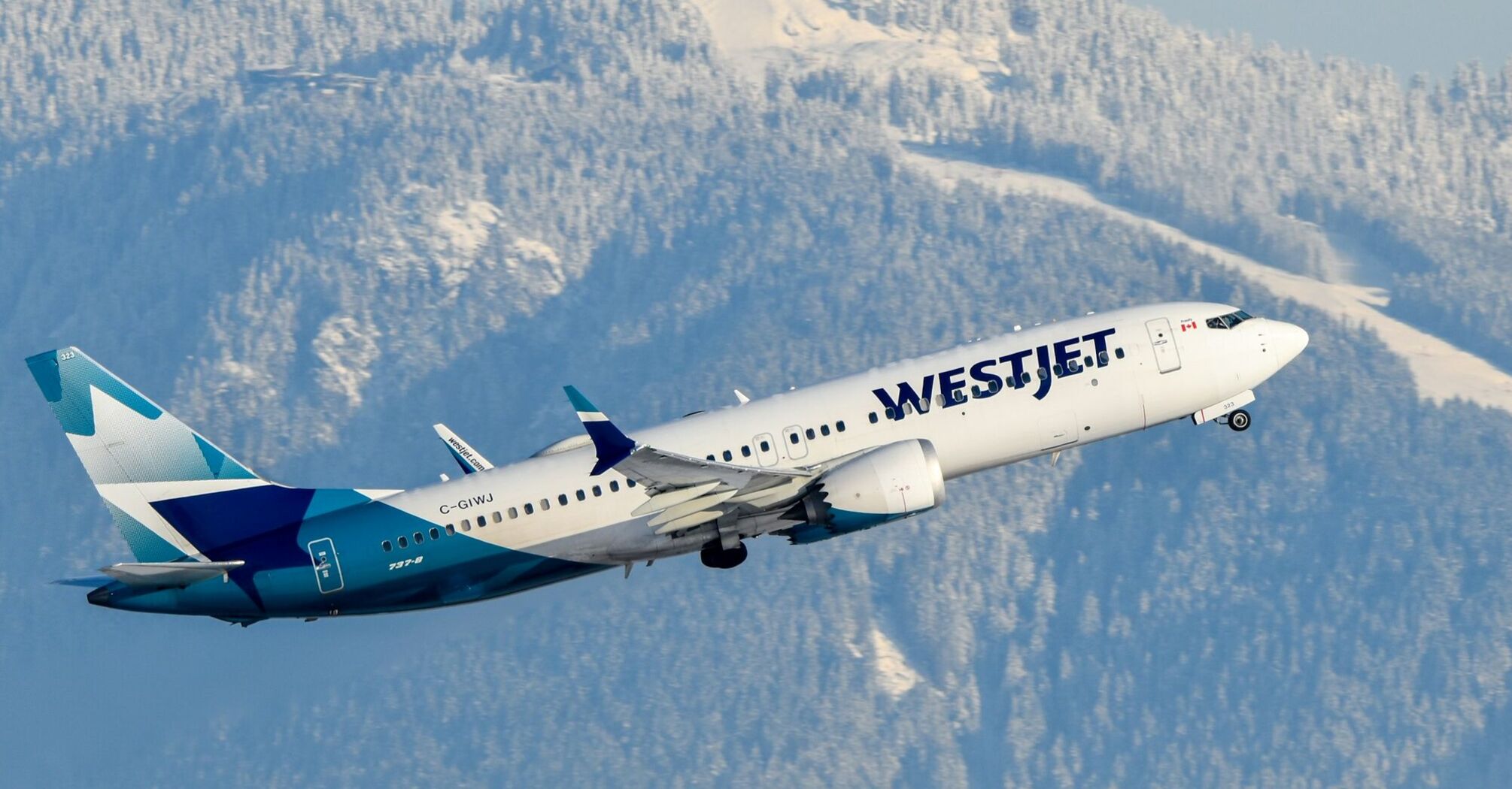 WestJet Boeing aircraft taking off with snowy mountains behind