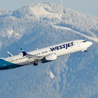 WestJet Boeing aircraft taking off with snowy mountains behind